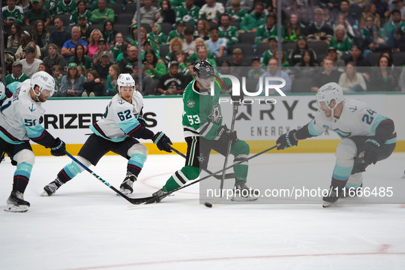 Wyatt Johnston #53 of the Dallas Stars defends the puck against Jamie Oleksiak #24 and Brandon Montour #62 of the Seattle Kraken during the...