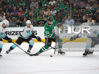 Wyatt Johnston #53 of the Dallas Stars defends the puck against Jamie Oleksiak #24 and Brandon Montour #62 of the Seattle Kraken during the...