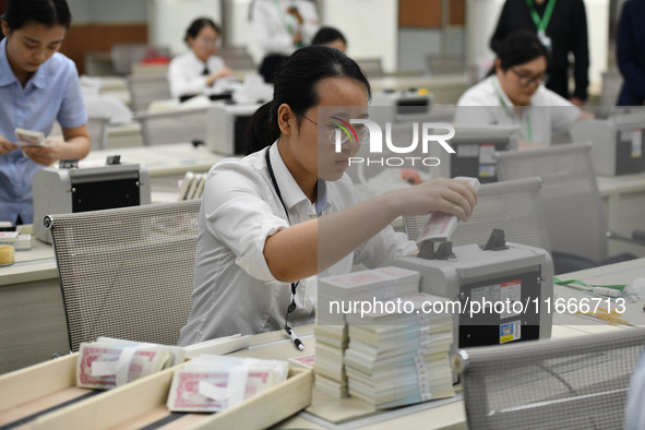 A bank employee uses a machine to count RMB during a vocational skills competition in the banking industry's currency gold and silver busine...