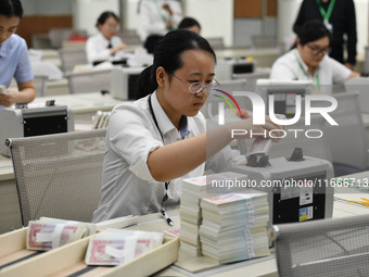 A bank employee uses a machine to count RMB during a vocational skills competition in the banking industry's currency gold and silver busine...