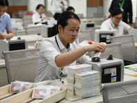 A bank employee uses a machine to count RMB during a vocational skills competition in the banking industry's currency gold and silver busine...