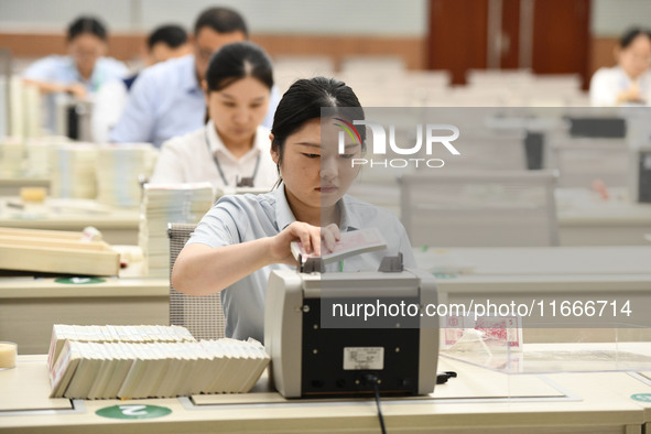 A bank employee uses a machine to count RMB during a vocational skills competition in the banking industry's currency gold and silver busine...