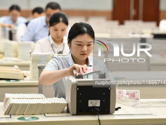 A bank employee uses a machine to count RMB during a vocational skills competition in the banking industry's currency gold and silver busine...