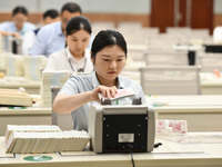 A bank employee uses a machine to count RMB during a vocational skills competition in the banking industry's currency gold and silver busine...