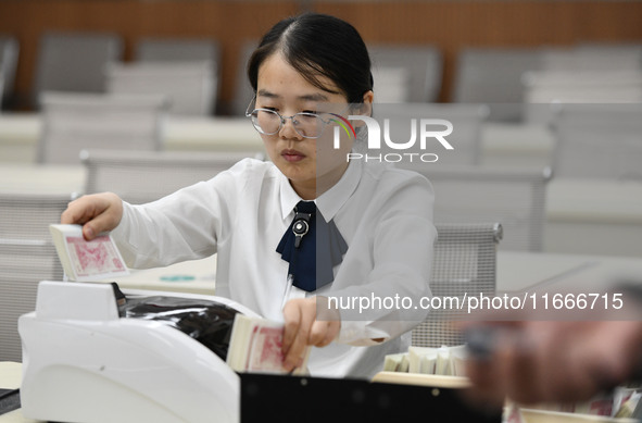 A bank employee uses a machine to count RMB during a vocational skills competition in the banking industry's currency gold and silver busine...