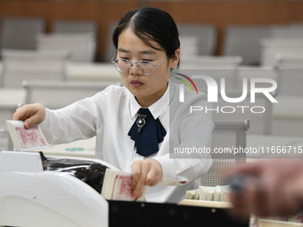 A bank employee uses a machine to count RMB during a vocational skills competition in the banking industry's currency gold and silver busine...