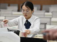 A bank employee uses a machine to count RMB during a vocational skills competition in the banking industry's currency gold and silver busine...