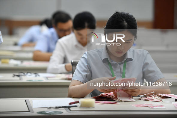 A contestant competes to identify counterfeit currency during a professional skills competition in the banking industry's currency and gold...