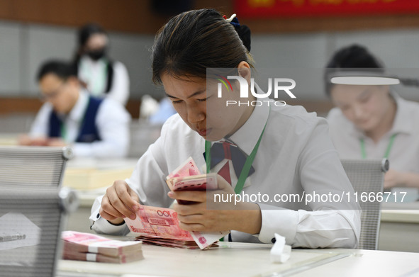 A contestant competes to identify counterfeit currency during a professional skills competition in the banking industry's currency and gold...