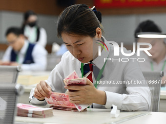 A contestant competes to identify counterfeit currency during a professional skills competition in the banking industry's currency and gold...