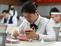 A contestant competes to identify counterfeit currency during a professional skills competition in the banking industry's currency and gold...