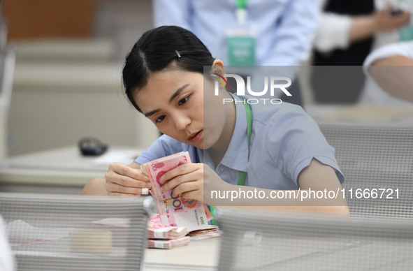 A contestant competes to identify counterfeit currency during a professional skills competition in the banking industry's currency and gold...