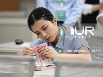 A contestant competes to identify counterfeit currency during a professional skills competition in the banking industry's currency and gold...