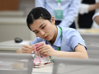 A contestant competes to identify counterfeit currency during a professional skills competition in the banking industry's currency and gold...