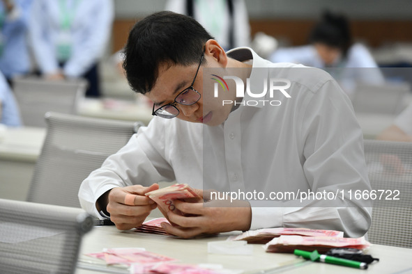 A contestant competes to identify counterfeit currency during a professional skills competition in the banking industry's currency and gold...