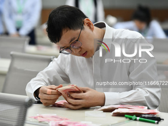 A contestant competes to identify counterfeit currency during a professional skills competition in the banking industry's currency and gold...