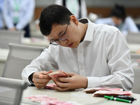 A contestant competes to identify counterfeit currency during a professional skills competition in the banking industry's currency and gold...