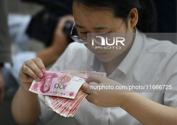 A contestant competes to identify counterfeit currency during a professional skills competition in the banking industry's currency and gold...