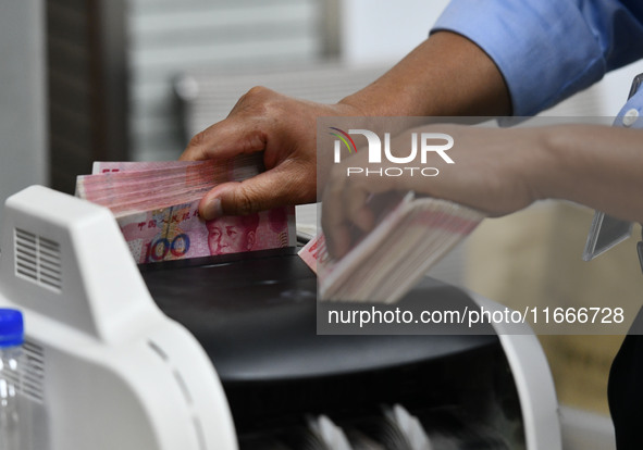 A bank employee uses a machine to count RMB during a vocational skills competition in the banking industry's currency gold and silver busine...