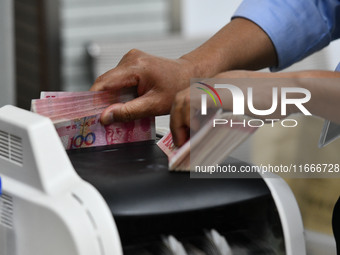 A bank employee uses a machine to count RMB during a vocational skills competition in the banking industry's currency gold and silver busine...