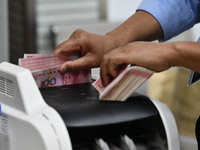 A bank employee uses a machine to count RMB during a vocational skills competition in the banking industry's currency gold and silver busine...