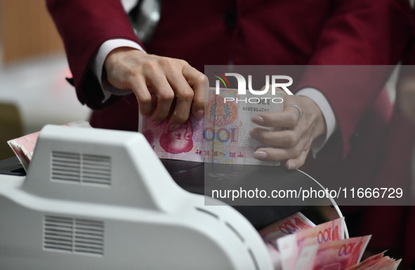 A bank employee uses a machine to count RMB during a vocational skills competition in the banking industry's currency gold and silver busine...