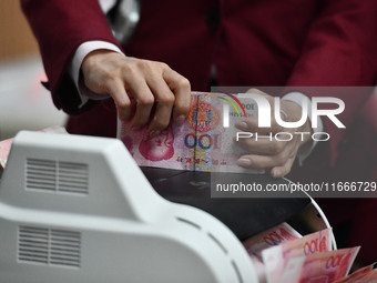 A bank employee uses a machine to count RMB during a vocational skills competition in the banking industry's currency gold and silver busine...