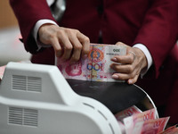 A bank employee uses a machine to count RMB during a vocational skills competition in the banking industry's currency gold and silver busine...