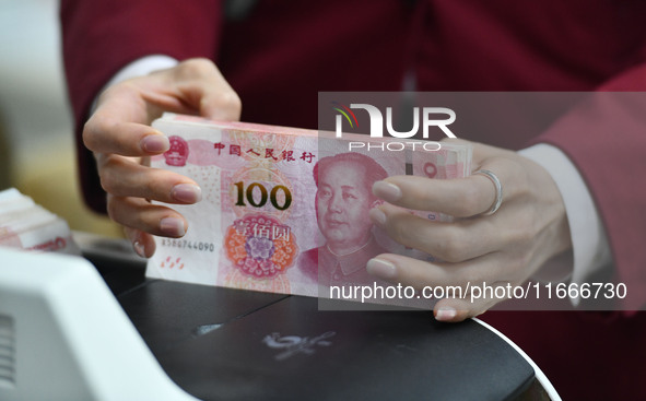 A bank employee uses a machine to count RMB during a vocational skills competition in the banking industry's currency gold and silver busine...