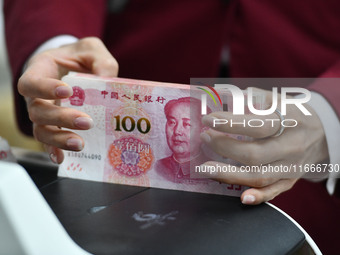 A bank employee uses a machine to count RMB during a vocational skills competition in the banking industry's currency gold and silver busine...