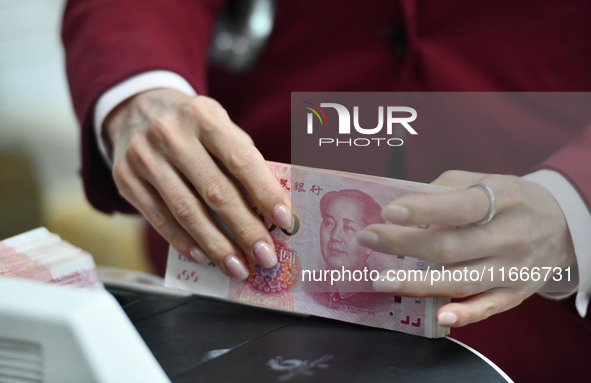 A bank employee uses a machine to count RMB during a vocational skills competition in the banking industry's currency gold and silver busine...