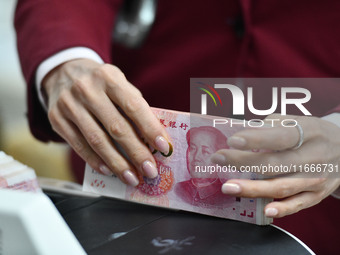 A bank employee uses a machine to count RMB during a vocational skills competition in the banking industry's currency gold and silver busine...