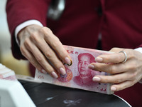 A bank employee uses a machine to count RMB during a vocational skills competition in the banking industry's currency gold and silver busine...