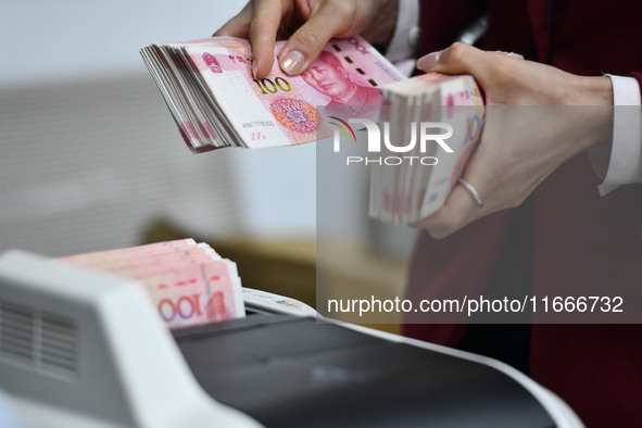 A bank employee uses a machine to count RMB during a vocational skills competition in the banking industry's currency gold and silver busine...