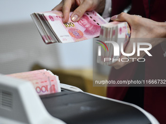 A bank employee uses a machine to count RMB during a vocational skills competition in the banking industry's currency gold and silver busine...