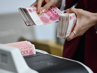 A bank employee uses a machine to count RMB during a vocational skills competition in the banking industry's currency gold and silver busine...