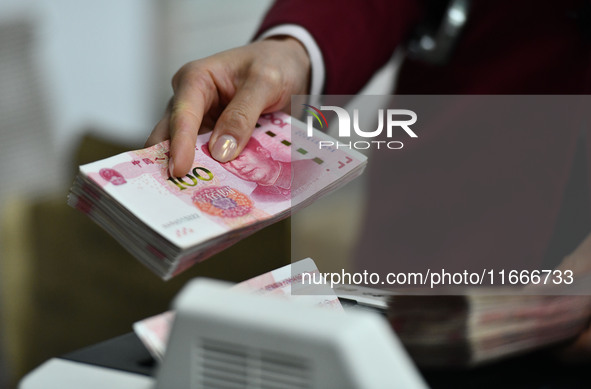 A bank employee uses a machine to count RMB during a vocational skills competition in the banking industry's currency gold and silver busine...