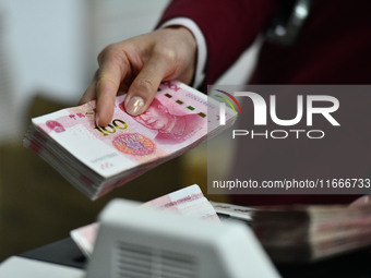 A bank employee uses a machine to count RMB during a vocational skills competition in the banking industry's currency gold and silver busine...