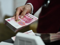 A bank employee uses a machine to count RMB during a vocational skills competition in the banking industry's currency gold and silver busine...