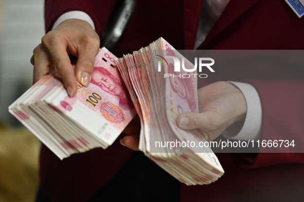 A bank employee uses a machine to count RMB during a vocational skills competition in the banking industry's currency gold and silver busine...