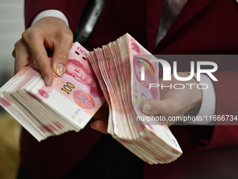 A bank employee uses a machine to count RMB during a vocational skills competition in the banking industry's currency gold and silver busine...