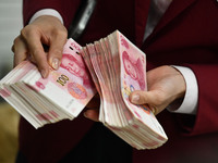 A bank employee uses a machine to count RMB during a vocational skills competition in the banking industry's currency gold and silver busine...