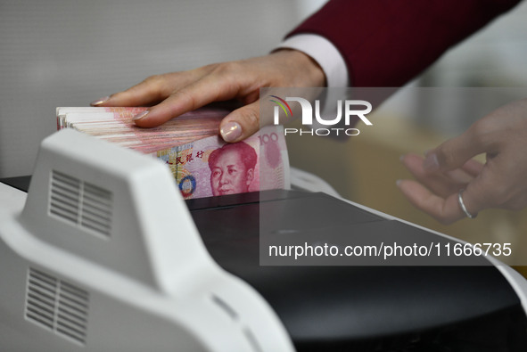 A bank employee uses a machine to count RMB during a vocational skills competition in the banking industry's currency gold and silver busine...