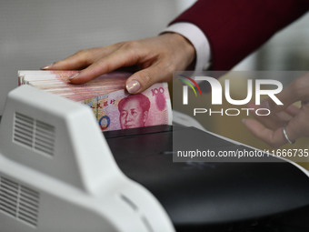 A bank employee uses a machine to count RMB during a vocational skills competition in the banking industry's currency gold and silver busine...