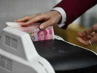 A bank employee uses a machine to count RMB during a vocational skills competition in the banking industry's currency gold and silver busine...