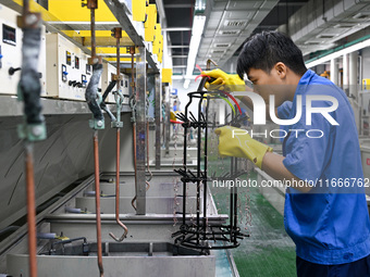 A worker electroplates metal jewelry at a jewelry processing plant in Jinhua, China, on October 15, 2024. (