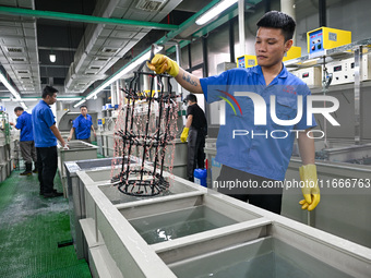 A worker electroplates metal jewelry at a jewelry processing plant in Jinhua, China, on October 15, 2024. (