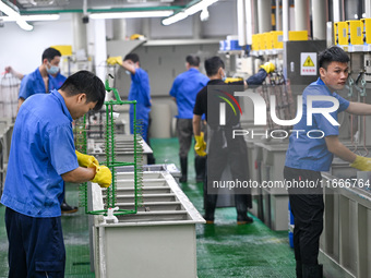 A worker electroplates metal jewelry at a jewelry processing plant in Jinhua, China, on October 15, 2024. (