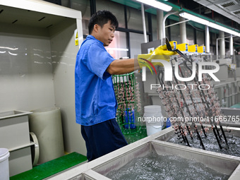 A worker electroplates metal jewelry at a jewelry processing plant in Jinhua, China, on October 15, 2024. (