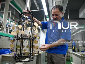 A worker electroplates metal jewelry at a jewelry processing plant in Jinhua, China, on October 15, 2024. (